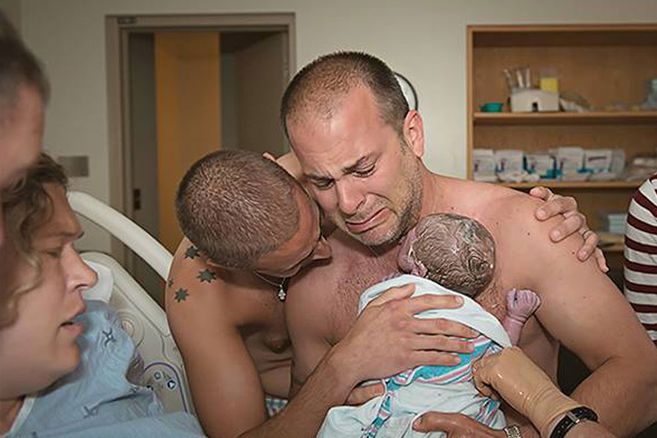 Zwei Väter halten ihren neugeborenen Sohn zum ersten Mal im Arm